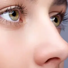 Nahaufnahme eines Gesichts mit Fokus auf das Auge und die Nase. Ein Tutorial zum nase schmaler schminken zeigt, wie man die Nase optisch verkleinert.