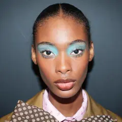 Ein auffälliges Silvester Make-up Look mit leuchtend türkisfarbenem Lidschatten und glänzenden Lippen.