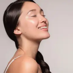 Ein lächelndes Gesicht mit strahlender, **glass skin**-ähnlicher Haut, die von Feuchtigkeit glänzt.