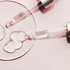 Zwei Pipetten geben klare Flüssigkeit auf eine Glasplatte. Perfekt, um BHA und Niacinamid zu kombinieren für reine Haut.