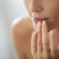 Frau trägt Lippenbalsam auf, um trockene Lippen zu behandeln. Sanfte Pflege für geschmeidige Lippen.