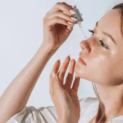 Frau trägt ein Serum auf, das Squalan enthält, um ihre Haut zu pflegen.