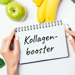Grüne Äpfel, Bananen, Sellerie, Spinat und Brokkoli – Zutaten für kollagenhaltige Lebensmittel, die auf einem Notizbuch mit der Aufschrift "Kollagen-Booster" liegen.