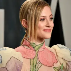 Ein Lächeln in Pfirsich-Nude-Tönen, das durch ein blumenverziertes Kleid und funkelnde Ohrringe unterstrichen wird.