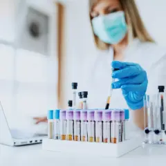 Wissenschaftlerin mit Maske und Handschuhen arbeitet mit Blutproben. Loreal tierversuche sind ein Thema, das hier nicht direkt gezeigt wird, aber die Forschung ist wichtig.
