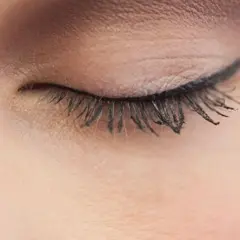 Ein geschlossenes Auge mit einem präzisen Lidstrich, der die Augenform betont. Lange, geschwungene Wimpern unterstreichen den eleganten Look.