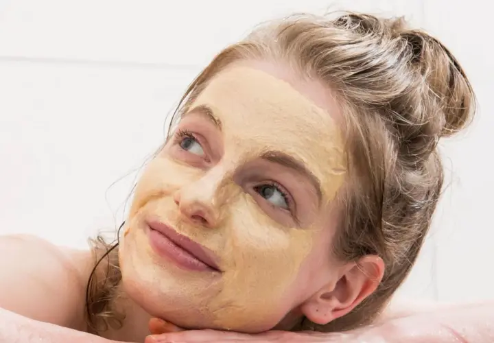 Frau mit Gesichtsmaske, die entspannt in die Ferne blickt. Tolle hautpflege tipps für strahlende Haut.