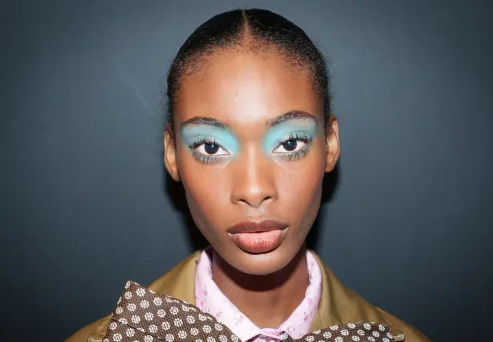 Ein auffälliges Silvester Make-up Look mit leuchtend türkisfarbenem Lidschatten und glänzenden Lippen.