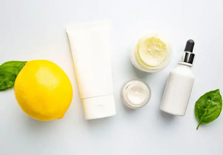 Kosmetikprodukte mit Zitrone, die an Retinol und Vitamin C erinnert, neben grünen Blättern.