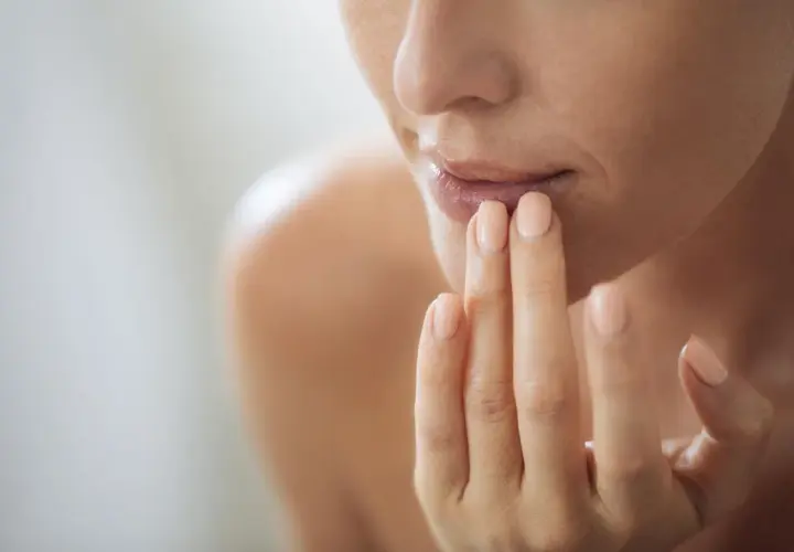 Frau trägt Lippenbalsam auf, um trockene Lippen zu behandeln. Sanfte Pflege für geschmeidige Lippen.