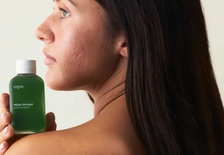 Sanfte Pflege für empfindliche Haut: Eine Frau hält eine Flasche mit mildem Reiniger.