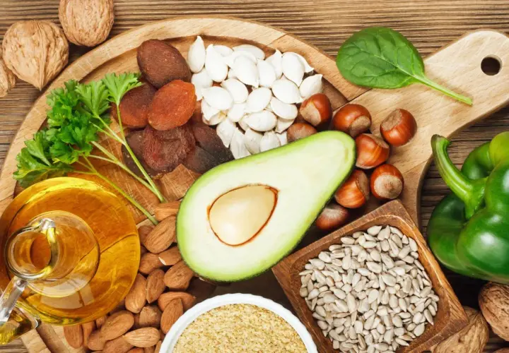 Reichhaltige Lebensmittel für gesunde **Vitamin E Haut**: Nüsse, Samen, Avocado, Öl, Trockenfrüchte und grünes Gemüse.