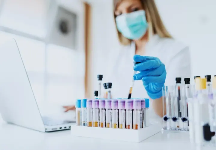 Wissenschaftlerin mit Maske und Handschuhen arbeitet mit Blutproben. Loreal tierversuche sind ein Thema, das hier nicht direkt gezeigt wird, aber die Forschung ist wichtig.