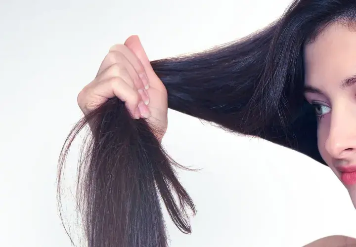 Frau mit dunklem Haar, das sie in der Hand hält. Tipps für trockene Haare, was tun?