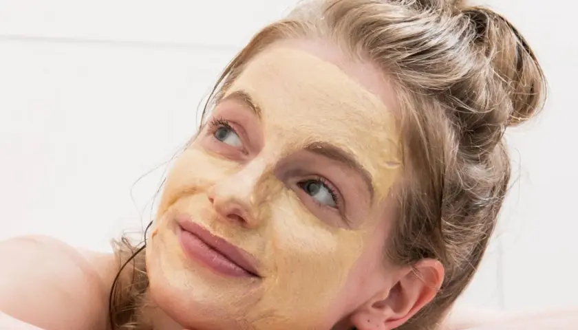 Frau mit Gesichtsmaske, die entspannt in die Ferne blickt. Tolle hautpflege tipps für strahlende Haut.