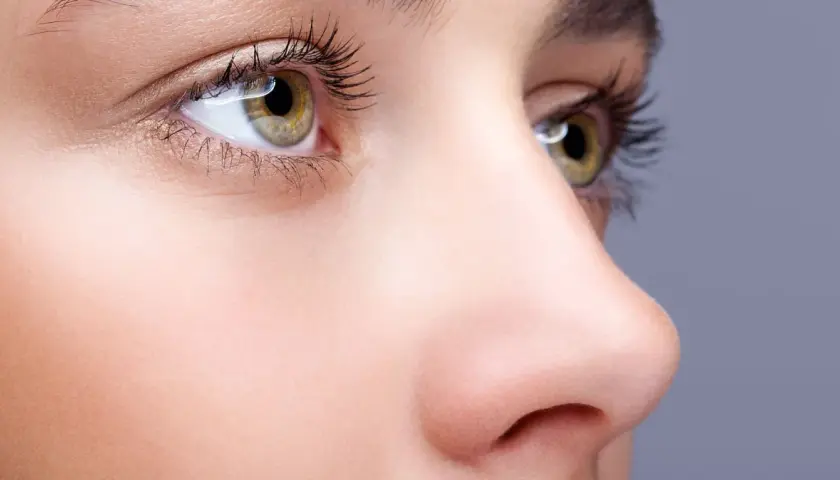 Nahaufnahme eines Gesichts mit Fokus auf das Auge und die Nase. Ein Tutorial zum nase schmaler schminken zeigt, wie man die Nase optisch verkleinert.