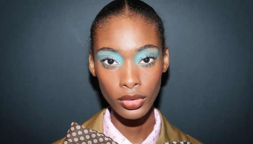 Ein auffälliges Silvester Make-up Look mit leuchtend türkisfarbenem Lidschatten und glänzenden Lippen.