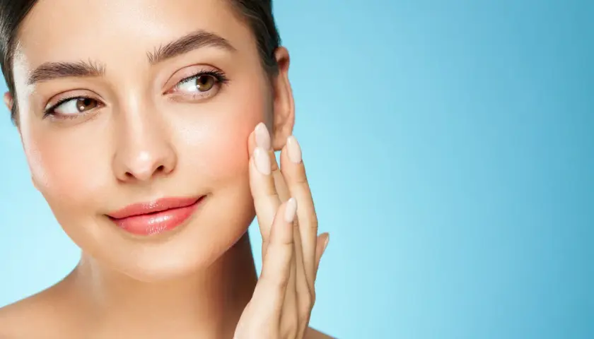 Sanfte Berührung auf rosiger Haut, die von Retinol und Niacinamid profitiert.