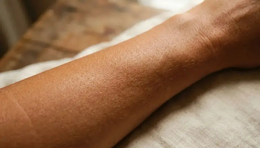 Gebräunte Haut am Unterarm, die Frage "wie lange bleibt man braun" beschäftigt viele nach dem Sommer.