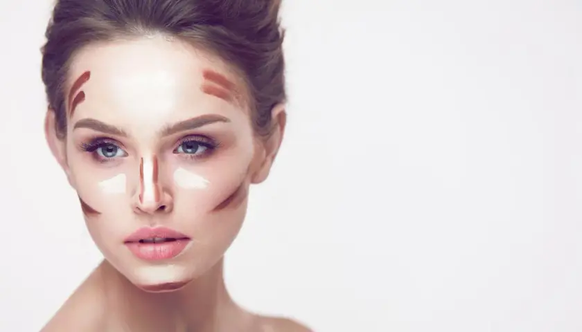Frauenkopf mit Konturen und hellem Concealer auftragen, bereit zum Verblenden für einen perfekten Look.