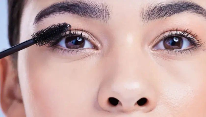 Eine Mascara-Bürste betont die Wimpern, um die schönen, runden Augen hervorzuheben.