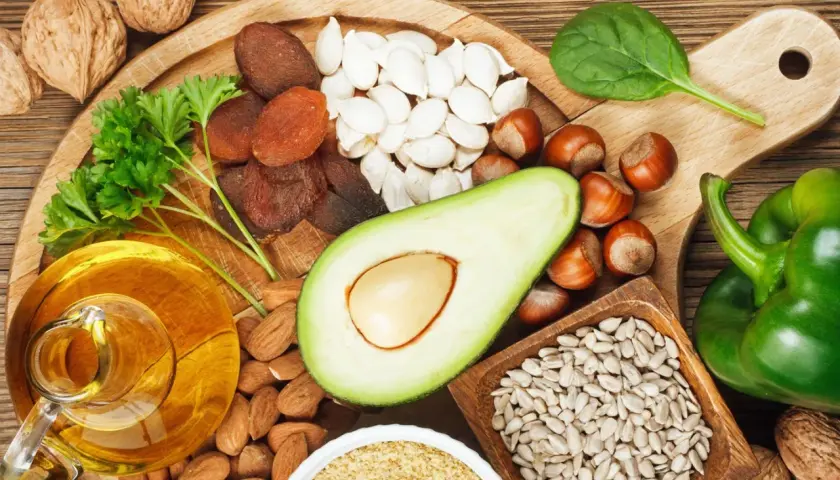 Reichhaltige Lebensmittel für gesunde **Vitamin E Haut**: Nüsse, Samen, Avocado, Öl, Trockenfrüchte und grünes Gemüse.