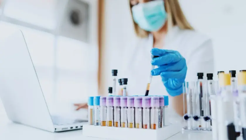Wissenschaftlerin mit Maske und Handschuhen arbeitet mit Blutproben. Loreal tierversuche sind ein Thema, das hier nicht direkt gezeigt wird, aber die Forschung ist wichtig.