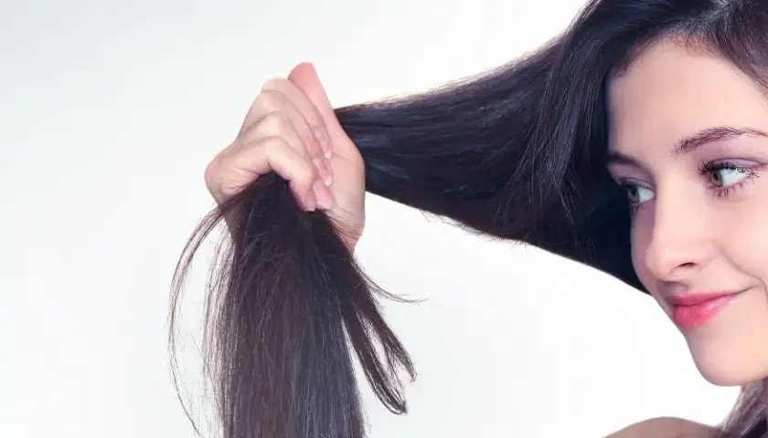 Frau mit dunklem Haar, das sie in der Hand hält. Tipps für trockene Haare, was tun?