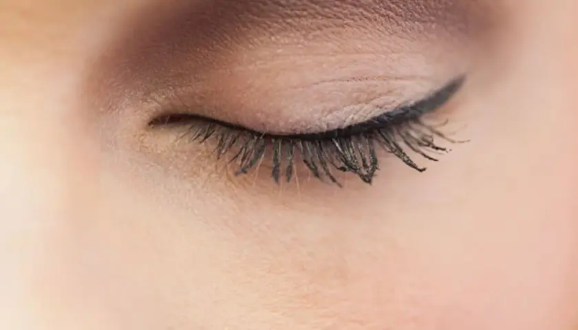 Ein geschlossenes Auge mit einem präzisen Lidstrich, der die Augenform betont. Lange, geschwungene Wimpern unterstreichen den eleganten Look.