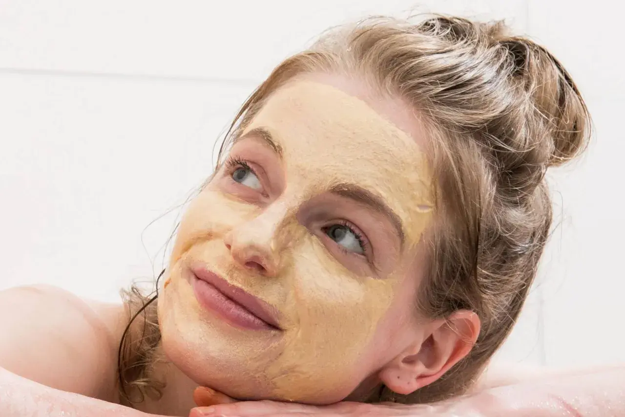 Frau mit Gesichtsmaske, die entspannt in die Ferne blickt. Tolle hautpflege tipps für strahlende Haut.