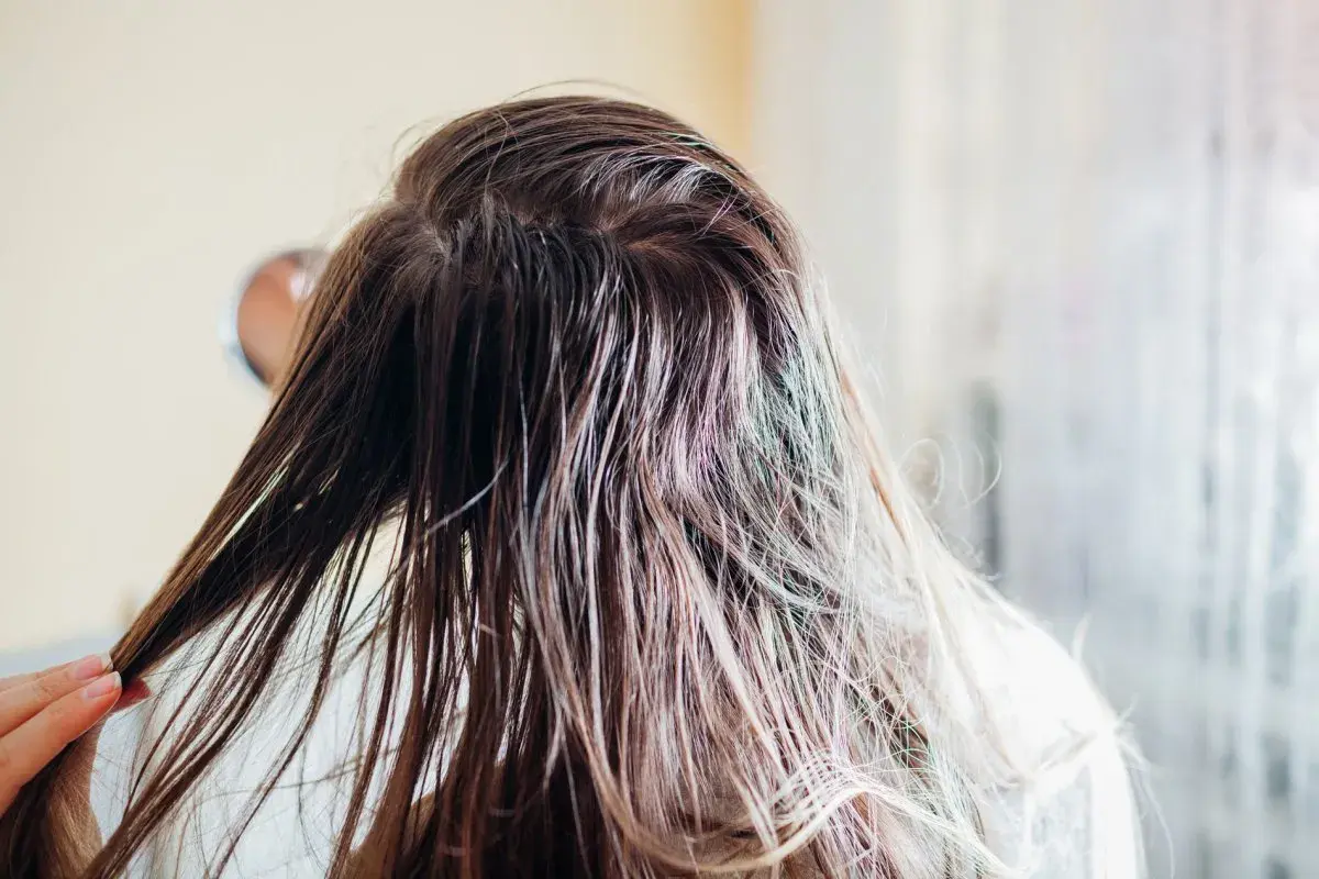Nasse Haare, die nur mit Wasser gewaschen werden. Eine Hand streicht durch die feuchten Strähnen, die leicht glänzen.