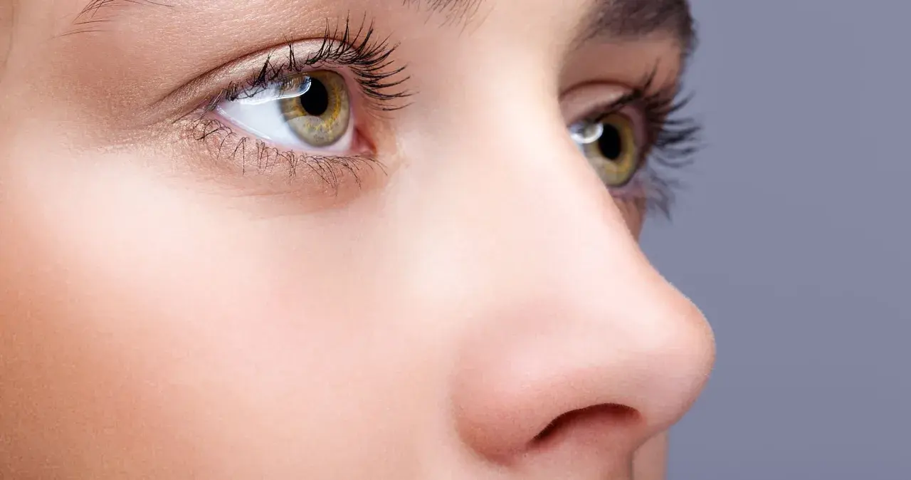 Nahaufnahme eines Gesichts mit Fokus auf das Auge und die Nase. Ein Tutorial zum nase schmaler schminken zeigt, wie man die Nase optisch verkleinert.