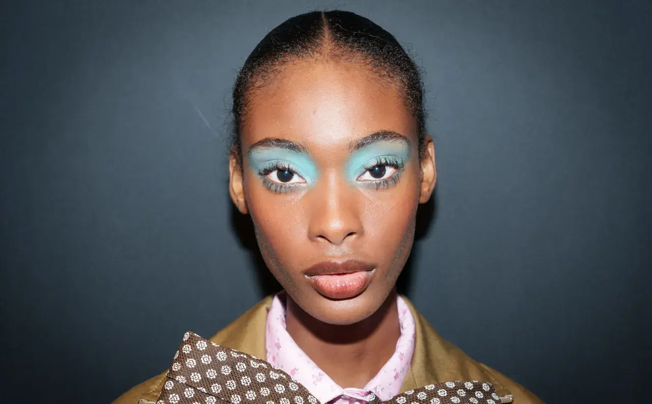 Ein auffälliges Silvester Make-up Look mit leuchtend türkisfarbenem Lidschatten und glänzenden Lippen.