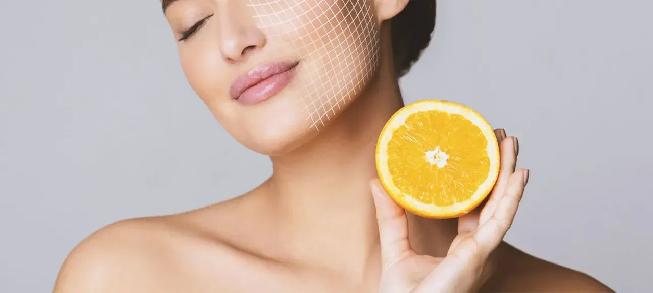 Frau mit Gitterlinien im Gesicht hält eine Orangenhälfte. Vitamin C gegen Pickel für strahlende Haut.