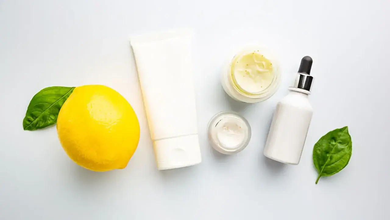 Kosmetikprodukte mit Zitrone, die an Retinol und Vitamin C erinnert, neben grünen Blättern.