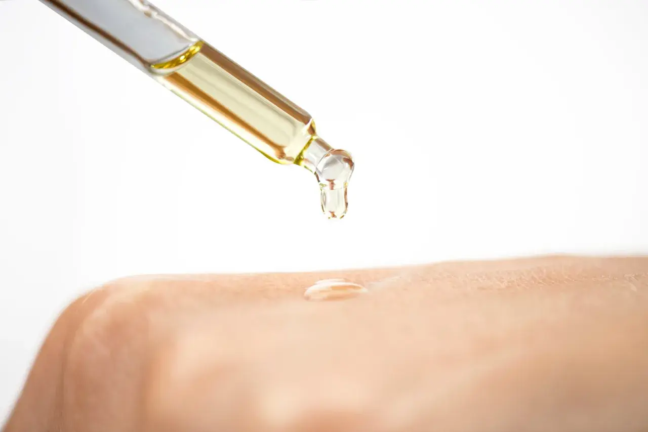 Ein Tropfen Öl mit Glycerin fällt auf die Haut.