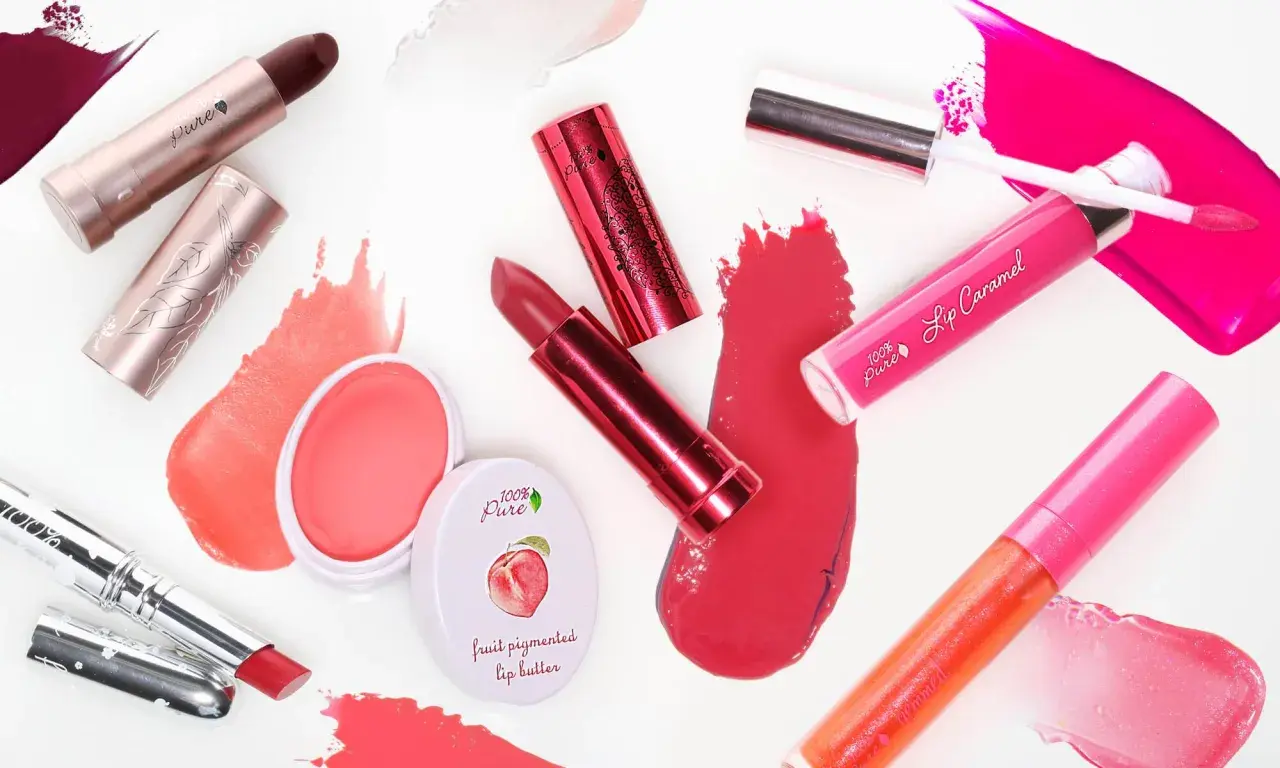 Verschiedene Lippenstifte und Lipglosse in Rottönen und Pink. Die Produkte bestehen aus natürlichen Inhaltsstoffen, wie Fruchtpigmenten.