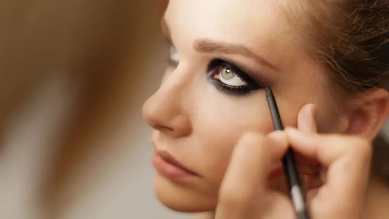 Ein Make-up-Artist kreiert dramatische smokey eyes mit einem Kajalstift.