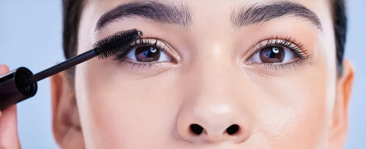 Eine Mascara-Bürste betont die Wimpern, um die schönen, runden Augen hervorzuheben.
