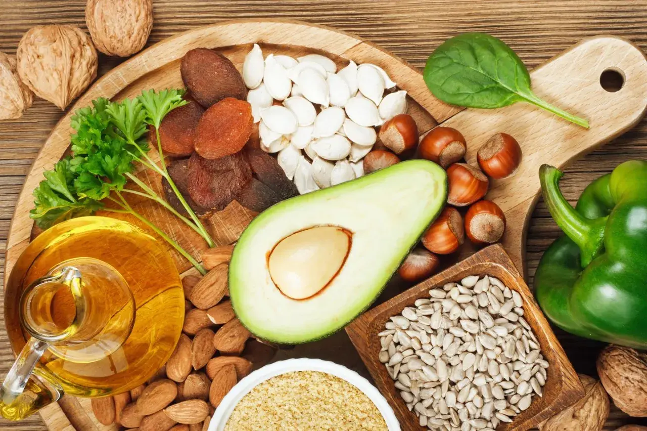 Reichhaltige Lebensmittel für gesunde **Vitamin E Haut**: Nüsse, Samen, Avocado, Öl, Trockenfrüchte und grünes Gemüse.