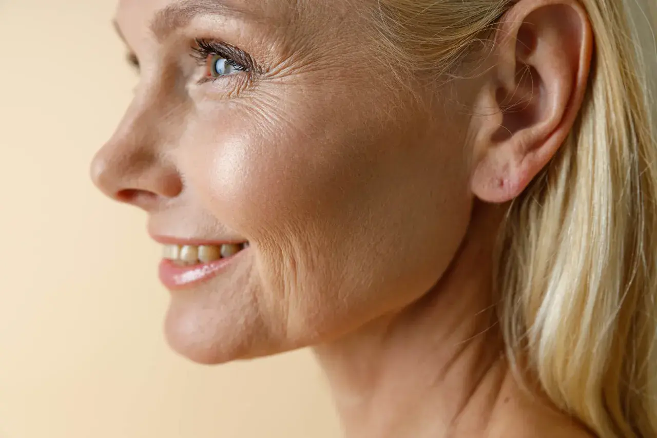 Profil einer lächelnden Frau mit sichtbaren Lachfalten um Mund und Augen. Ihr blondes Haar umrahmt ihr Gesicht.