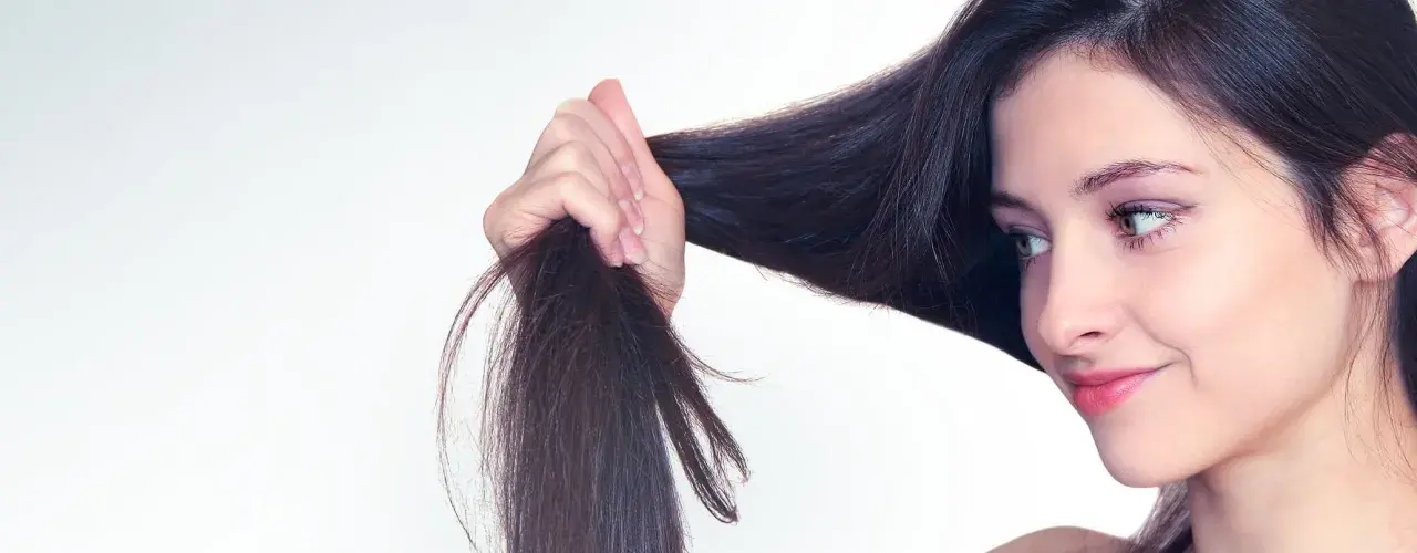 Frau mit dunklem Haar, das sie in der Hand hält. Tipps für trockene Haare, was tun?
