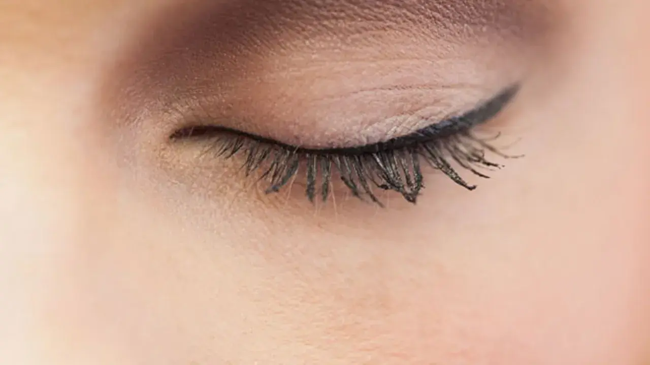 Ein geschlossenes Auge mit einem präzisen Lidstrich, der die Augenform betont. Lange, geschwungene Wimpern unterstreichen den eleganten Look.
