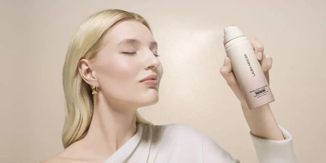 Frau mit geschlossenen Augen sprüht sich mit einem Laura Mercier Setting Spray ins Gesicht. Der Unterschied zwischen Setting und Fixing Spray wird hier deutlich.