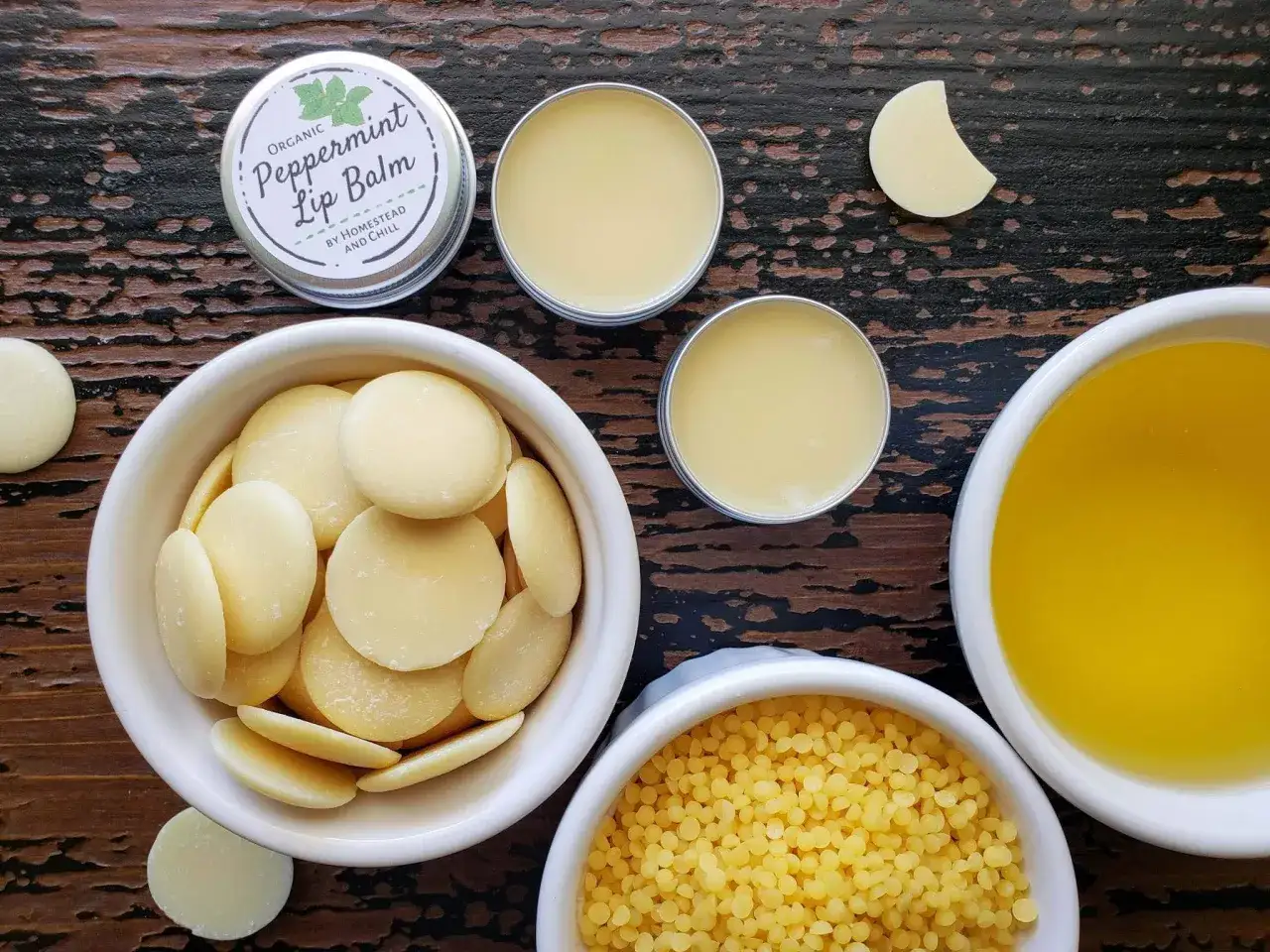 Zutaten f&uuml;r Lippenbalsam selber machen: Kakaobutter, Bienenwachs, &Ouml;l und eine Dose fertigen Lippenbalsam.