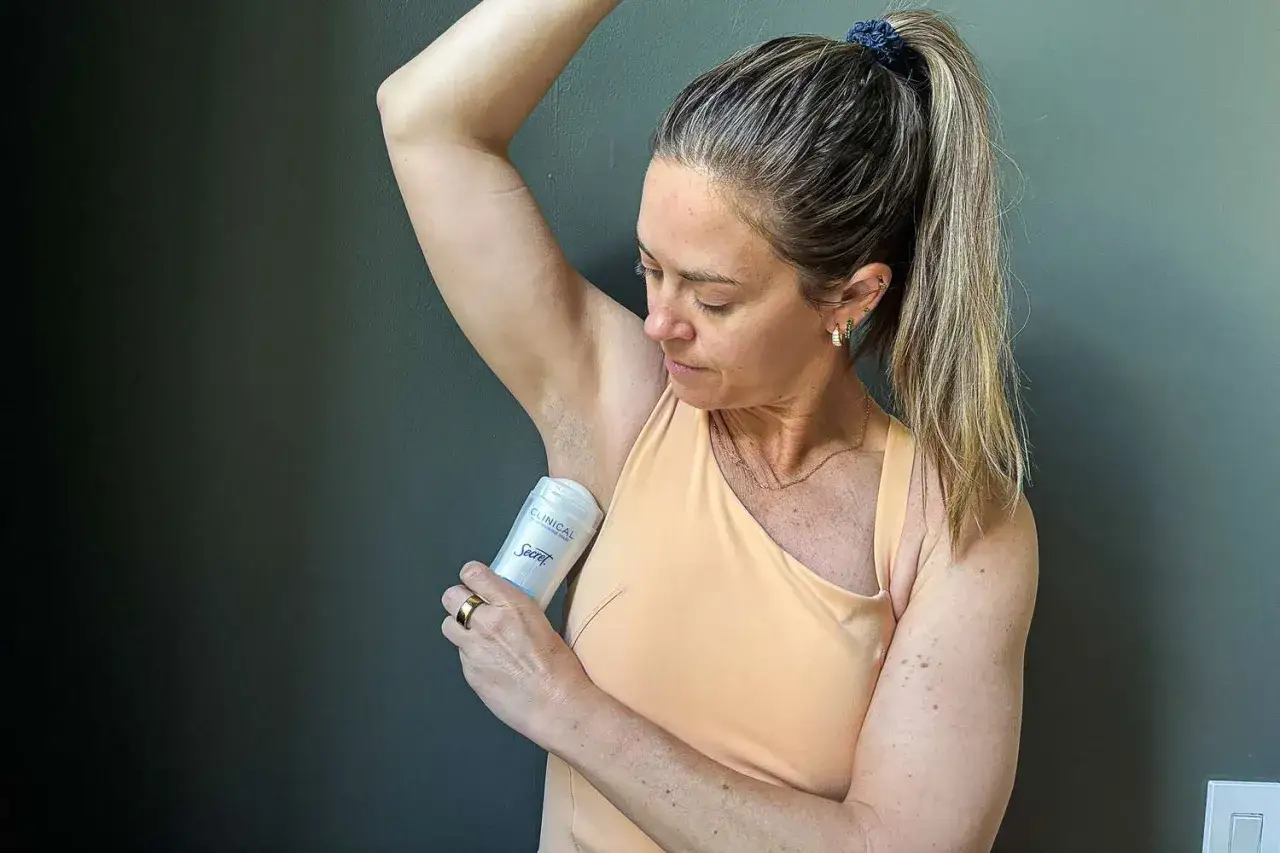 Frau wendet ein Secret Clinical Antiperspirant Spray an, um sich vor Schweiß zu schützen.