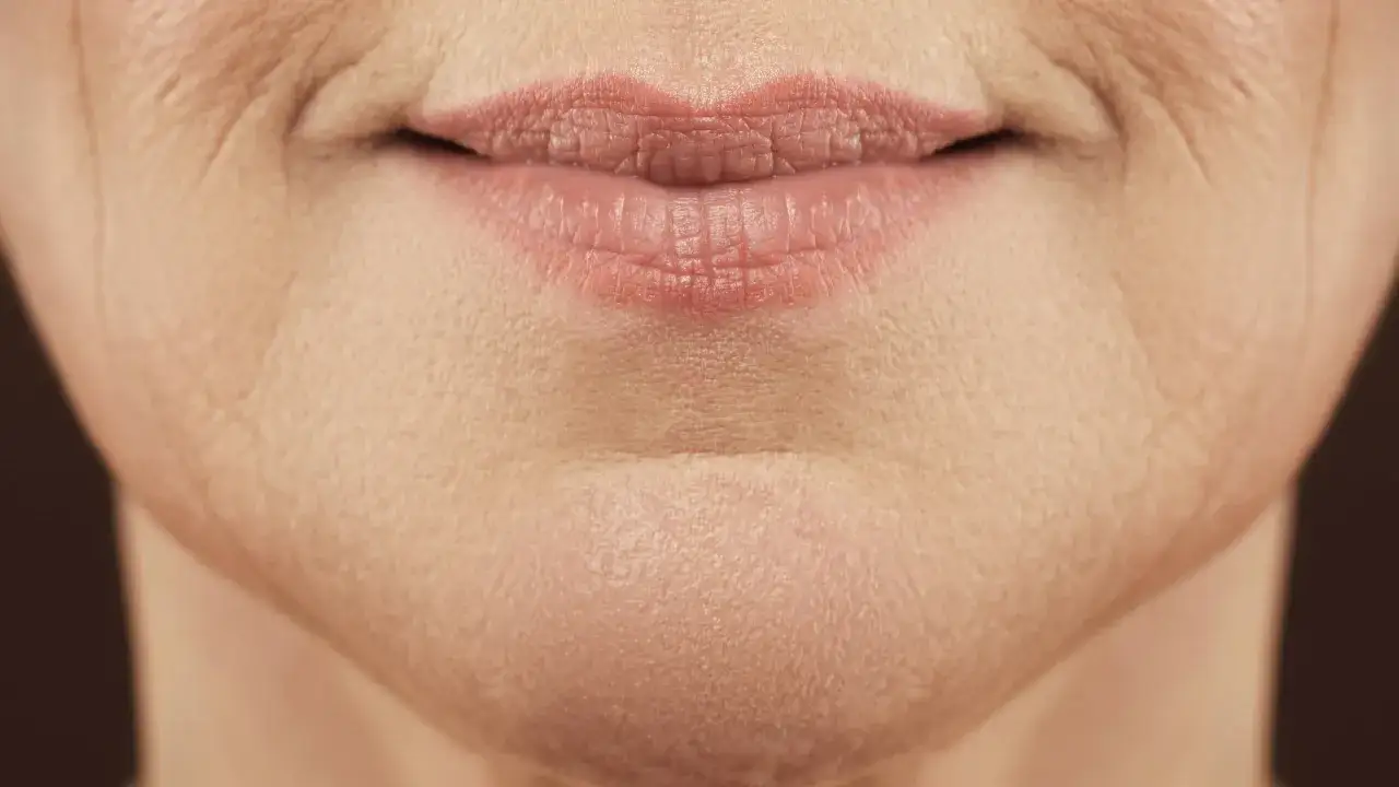 Nahaufnahme von Lippen und Kinn einer Frau, die zeigt, wie unreine Haut mit 40 aussehen kann, mit feinen Linien und Textur.
