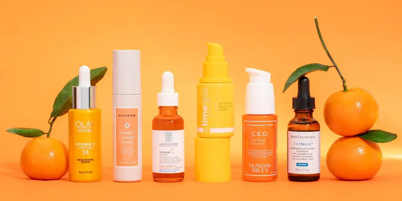 Mehrere Vitamin C Seren f&uuml;r strahlende Haut, umgeben von frischen Orangen.