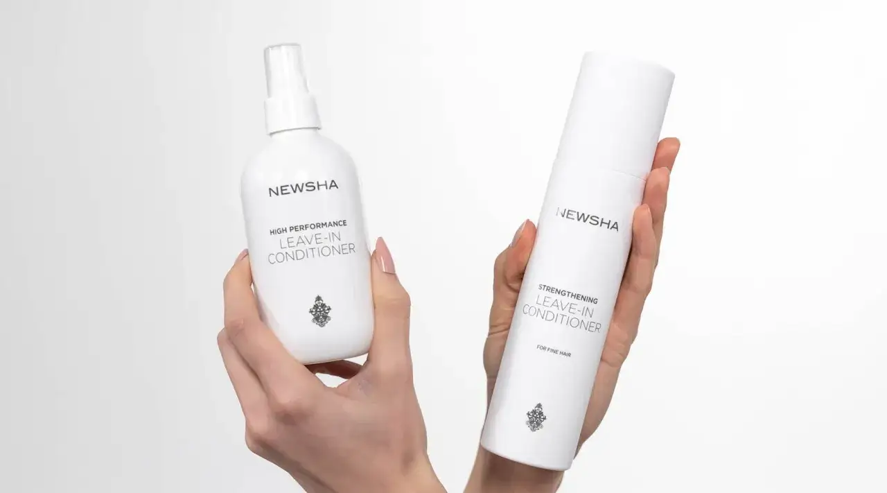 Zwei NEWSHA Leave-In Conditioner Flaschen in Händen, die das Haarwachstum anregen sollen.